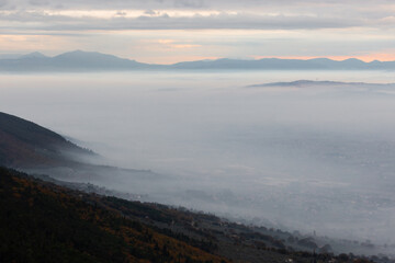 Mist and fog between valley and layers of mountains and hills at dusk, in Umbria (Italy)