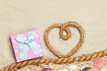 Gift box and rope in heart shape near net and shells