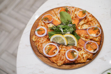 Smoked Salmon Pizza. Italian pizza topped with cheese and smoked salmon with salad on table at restaurant. (Top view)
