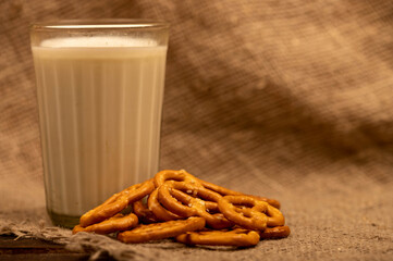 Salted breadsticks and salted pretzels in bulk and a glass of milk on the table.