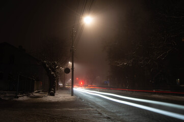 Night photo of a foggy street with car lights