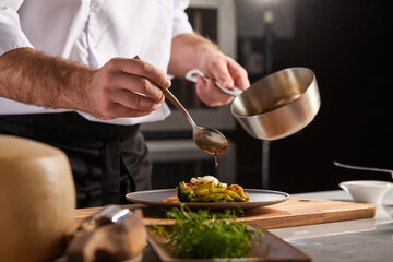 Cook adding some sauce to dish. Cropped chef preparing food, meal, in kitchen, chef cooking, Chef decorating dish, closeup