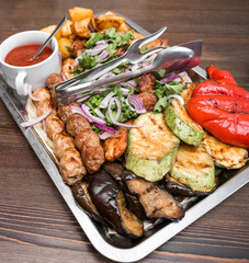 dish with vegetables meat kebab and potatoes greens sauce