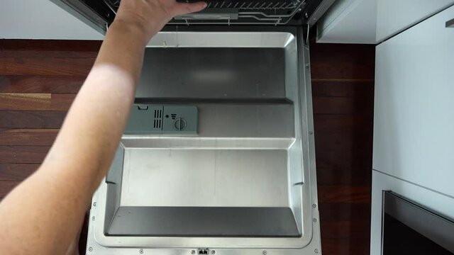 POV (point of view) of a woman placing dishes in kitchen dishwasher
