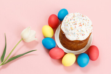 Easter cake on a plate, eggs and tulip flower with pink background.