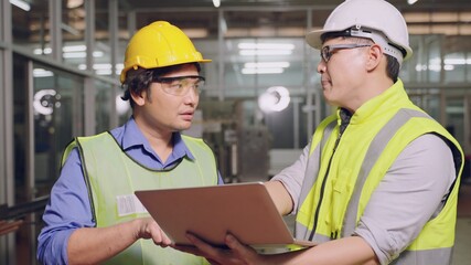 Asian manager feeling upset with the engine machine of the factory arguing about planning procedure of work, he scolding industrial workers for low level of quality standing in factory workshop
