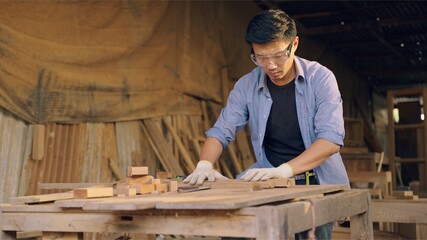 Professional asian carpenter working on wood craft in workshop to produce wooden furniture during the day. DIY maker and carpentry work concept.