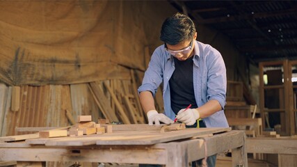Professional asian carpenter working on wood craft in workshop to produce wooden furniture during the day. DIY maker and carpentry work concept.