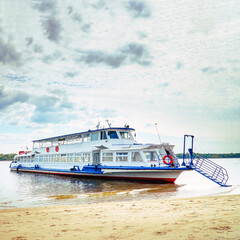 Pleasure boat on the shore of a large river on sunny day