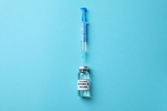 Vial Of Covid - 19 Vaccine And Syringe On Blue Background