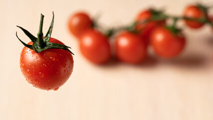 Cherry tomato in drops of water and tomatoes on a beige background