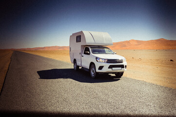Fototapeta na wymiar Motor home in the desert / Traveling with the camper, on a road through the desert, Africa.