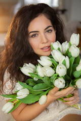 Obraz na płótnie Canvas Portrait of a beautiful young woman with bunch of white tulips.