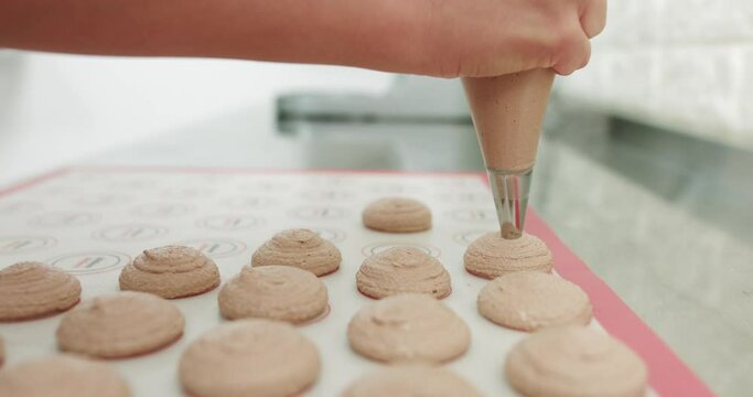 Chef Making Base For Preparation Macaron Dessert. Close-Up Of Extruding Brawn Creme From Piping Bag On Metal Tray For Baking Base Of Macaron Dessert. Concept Of Baking, Cooking