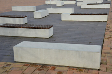 concrete white bench block and wave shape in the park on a dark cobbled square, clean concrete surface gray brown white pedestrian and rest area at the skate park for young people, teenagers