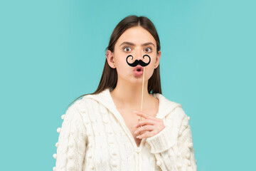 Crazy emotions. Just having fun. Woman holding fake mustache on her face. Suprised girl with...