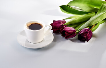 Fototapeta na wymiar cup of blakc coffee and purple tulips
