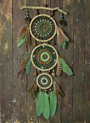 Obraz na płótnie Canvas Beautiful handmade boho dreamcatcher with green feathers and beads