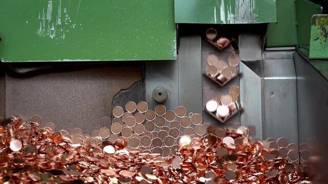 Coins manufactured in money mint machine, steel galvanized with copper, real time, printing money fueling inflation concept, debt monetization