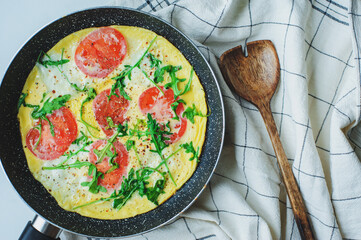 tasty italian style vegetarian breakfast - fried eggs frittata ot omelete with mozarella cheese, arugula and tomatoes