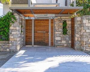 contemporary house main entrance natural wood door and stone covered wall by the sidewalk, Athens Greece