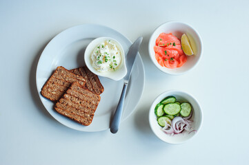 tasty healthy breakfast - salmon and avocado toast with cream cheese, cucumber and red onion on white background