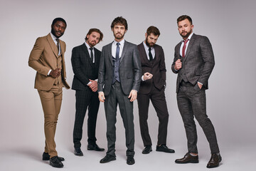 bearded brutal guys in classic suits posing with serious facial expression, young men in tux looking at camera, smart and intelligent. portrait