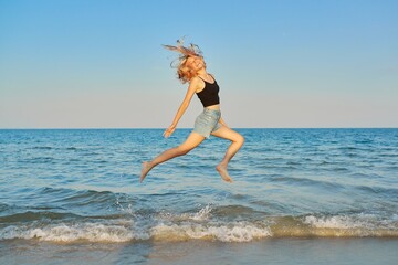 Naklejka premium Young beautiful woman flying over the sea, happy female jumping over water