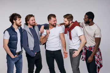 Group of happy diverse men in casual urban style clothes posing at camera, stand together having talk and cmile, laugh. isolated white background