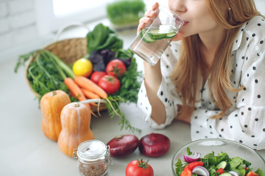 Woman on a diet. Young and happy woman eating healthy salad sitting on the table with green fresh ingredients indoors. High quality photo