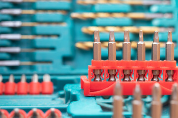 Drill bit kit, close up. Hardware backdrop texture. Blue kit with a variation red sets of drills and screwdriver. Defocused and abstract varieties of driver bit sets. Focus on driver bits in  center.