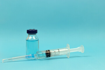 Medical concept - syringe and medical injection vial on blue background