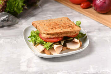 Sandwich with ham and fresh salad on the plate.