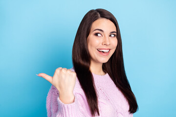 Photo of young cheerful girl happy smile look indicate thumb empty space ad promo select recommend isolated over blue color background