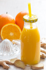 Healthy and fresh orange juice with addition of ginger on white wooden table