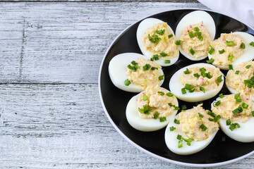 stuffed eggs with crab sticks, mayonnaise and green onion on black plate
