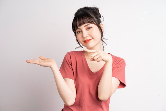 Young Asian woman posing on white background, using finger to pointing and showing, hand gesture