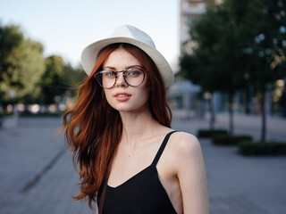 beautiful woman in hat outdoors in nature near buildings