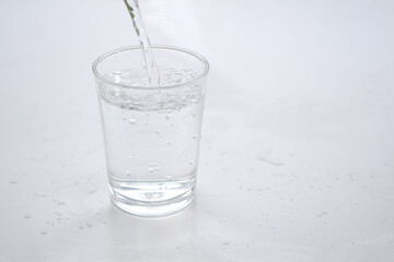 Pouring pure water into a glass on wood with wite background. healthy lifestyle and ideal for environmental protection concept.