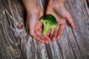 Selective focus of the hands from a girl with broccoli for a healthy meal
