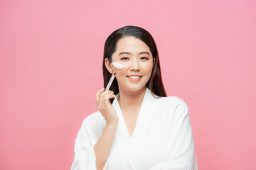 Beauty face care. Woman doing face massage with rose quartz face roller for spa skin care treatment...