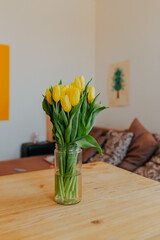 Bright fresh yellow tulips on white background. Bunch of yellow tulips in big glass jar. Spring flowers in glass vase.