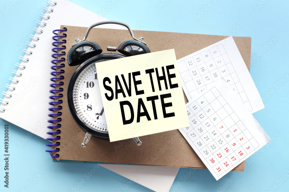 Aufkleber save the date. text on the sticker attached to the alarm clock. alarm clock on notepad on blue backg