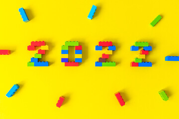 multicolored numbers 2022 from kids constructor set on isolated yellow background with place for text