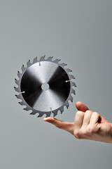Metal silver Circular Saw Blade for wood work isolated on gray background in male hands, copy space