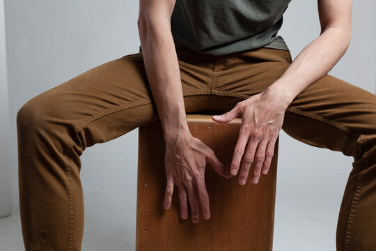 White man hands playing cajon on a white background.