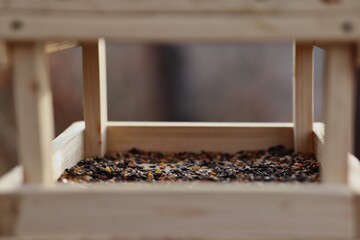 Close-up of Wooden Birdhouse with Mix of Seeds. Beautiful Bird Feeder Outside.