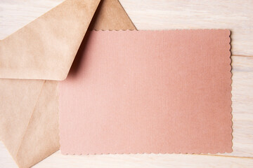 Craft envelope and blank card with copy space on light wooden background