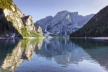 Croda del Becco peak in the bottom of the Braies lake towards sunset with boats moored, South Tyrol, Italy. Concept: relaxation in nature, famous natural places, film sets