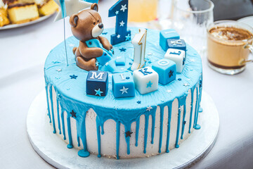 Niebieski tort czekoladowy ze zdobieniem w postaci misia z okazji pierwszych urodzin Mikołaja.